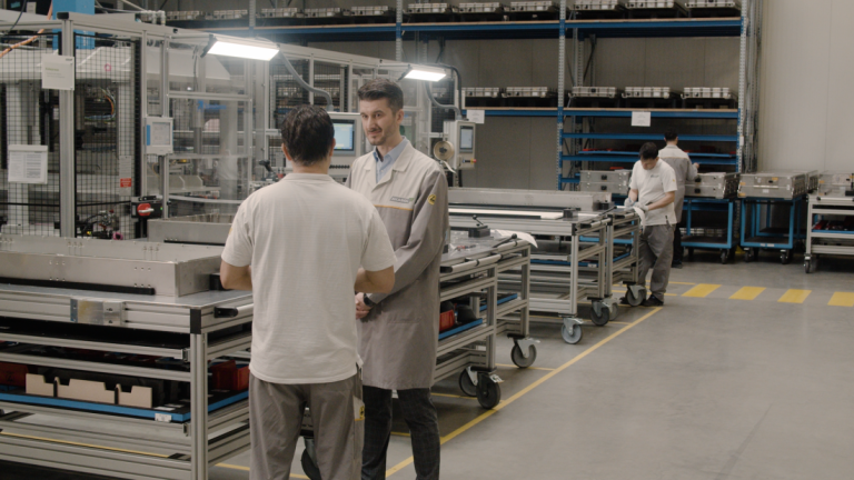 Ein Mitarbeiter von BorgWarnder Akasol in Darmstadt zeigt einem Mitarbeiter von Stäubli aus der Schweiz die Produktionshalle in Langen
